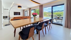 Un comedor moderno con una mesa larga, sillas y un jarrón de flores.