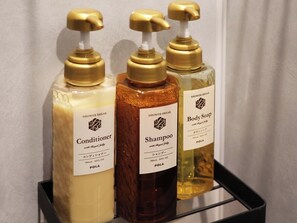 Tres botellas de productos de baño sobre una repisa.