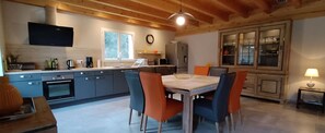 Eine moderne Küche mit grauen Schränken, einem eingebauten Ofen, einer Kaffeemaschine und einem Esstisch mit orangefarbenen Stühlen.