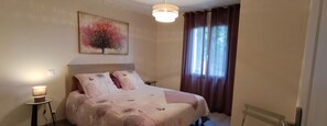 A bedroom with a bed, a bedside table, a lamp, a window with curtains, and a painting on the wall. - The Shepherdess's Farmhouse (Chantemerle-lès-Grignan)