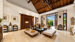 A spacious living area with a high ceiling, a large window, and a view of greenery outside. - Villa V Seminyak (Badung)