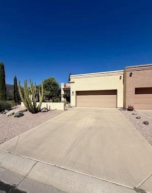 A residential property with a garage, a driveway, and a cactus in the landscaping.