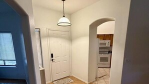 A hallway with wooden flooring, a white door, and a ceiling light fixture.