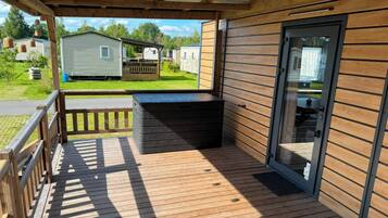 Een overdekt buitengebied met een houten terras, een ingebouwde bank en een schuifdeur naar een overdekt terras.