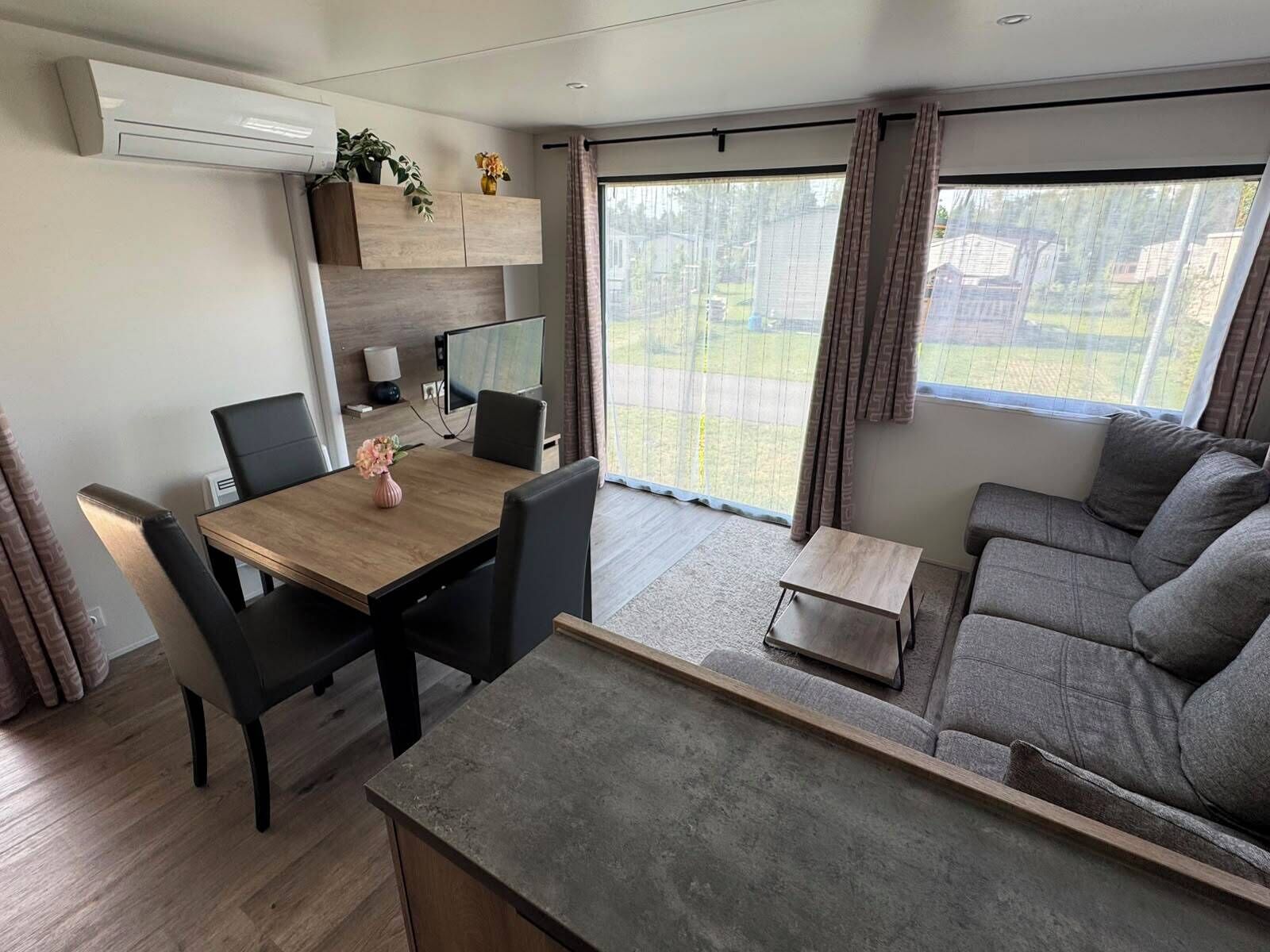 Een moderne woonkamer met een bank, een eettafel met stoelen, een bijzettafeltje en een televisie.