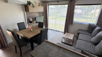 Een moderne woonkamer met een bank, een eettafel met stoelen, een bijzettafeltje en een televisie.