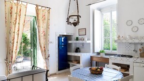 Uma cozinha com geladeira azul, painel de azulejos branco e uma mesa de jantar com toalha de mesa xadrez.