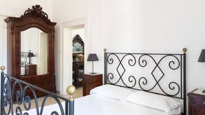 Quarto com cama, cômoda de madeira, espelho e cabeceira de metal.