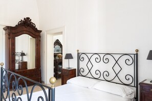 A bedroom with a bed, a wooden dresser, a mirror, and a metal headboard. - La Casina 1805 by Wonderful Italy (Bari)