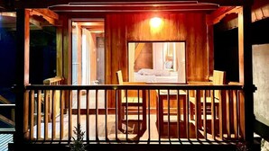 A wooden balcony with a view of a bedroom.