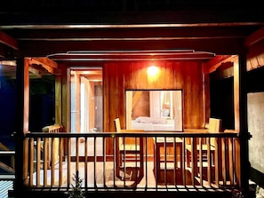 Un balcón de madera con vista a un dormitorio.