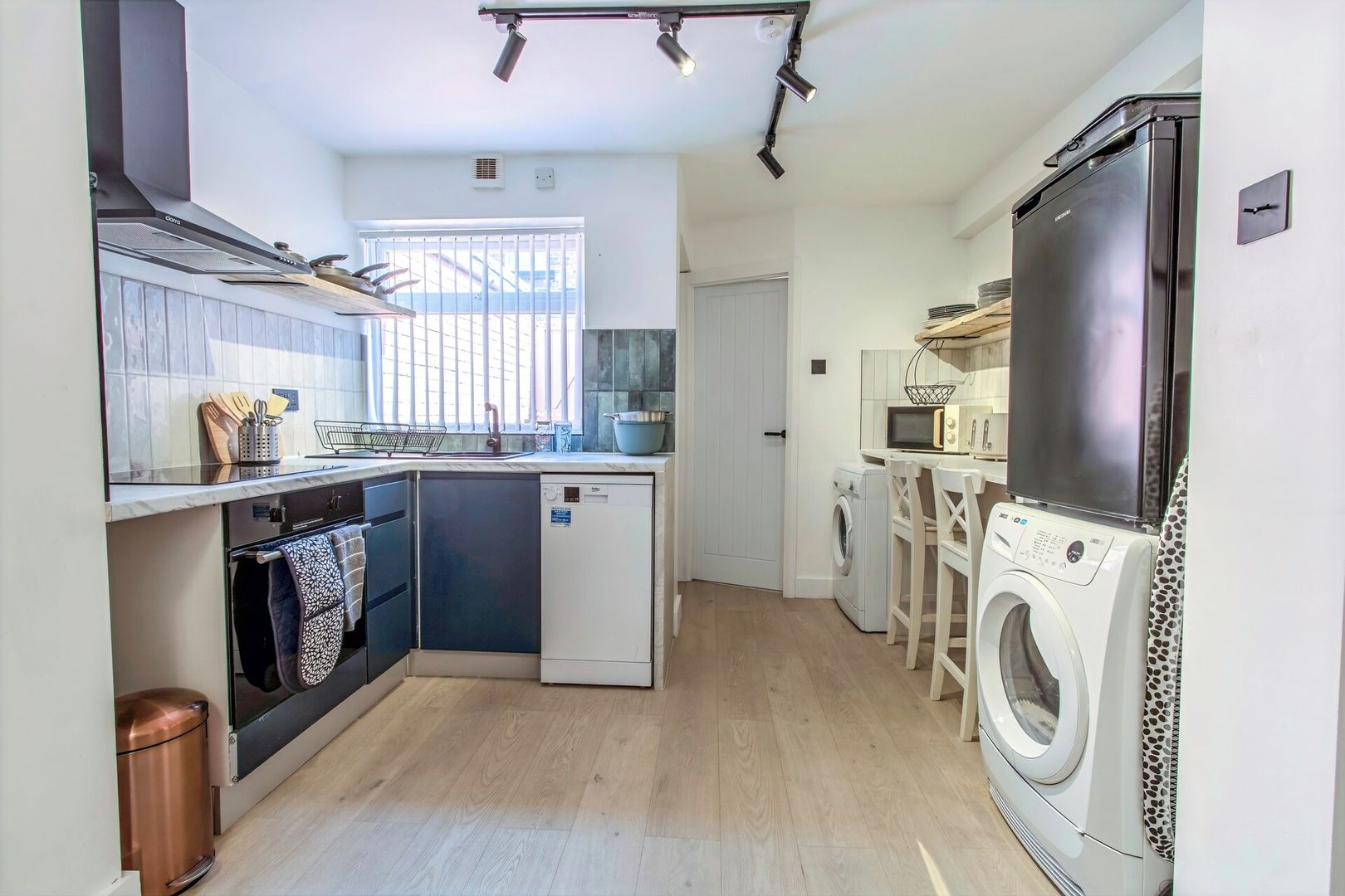 Een praktische keuken met een vaatwasser, wasmachine en magnetron.