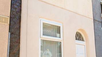 Ein Gebäude mit einer weißen Tür, einem Fenster mit weißem Rahmen und einer Ziegelwand.
