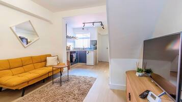 Un salon moderne avec un canapé, une petite table et un téléviseur posé sur un meuble en bois.