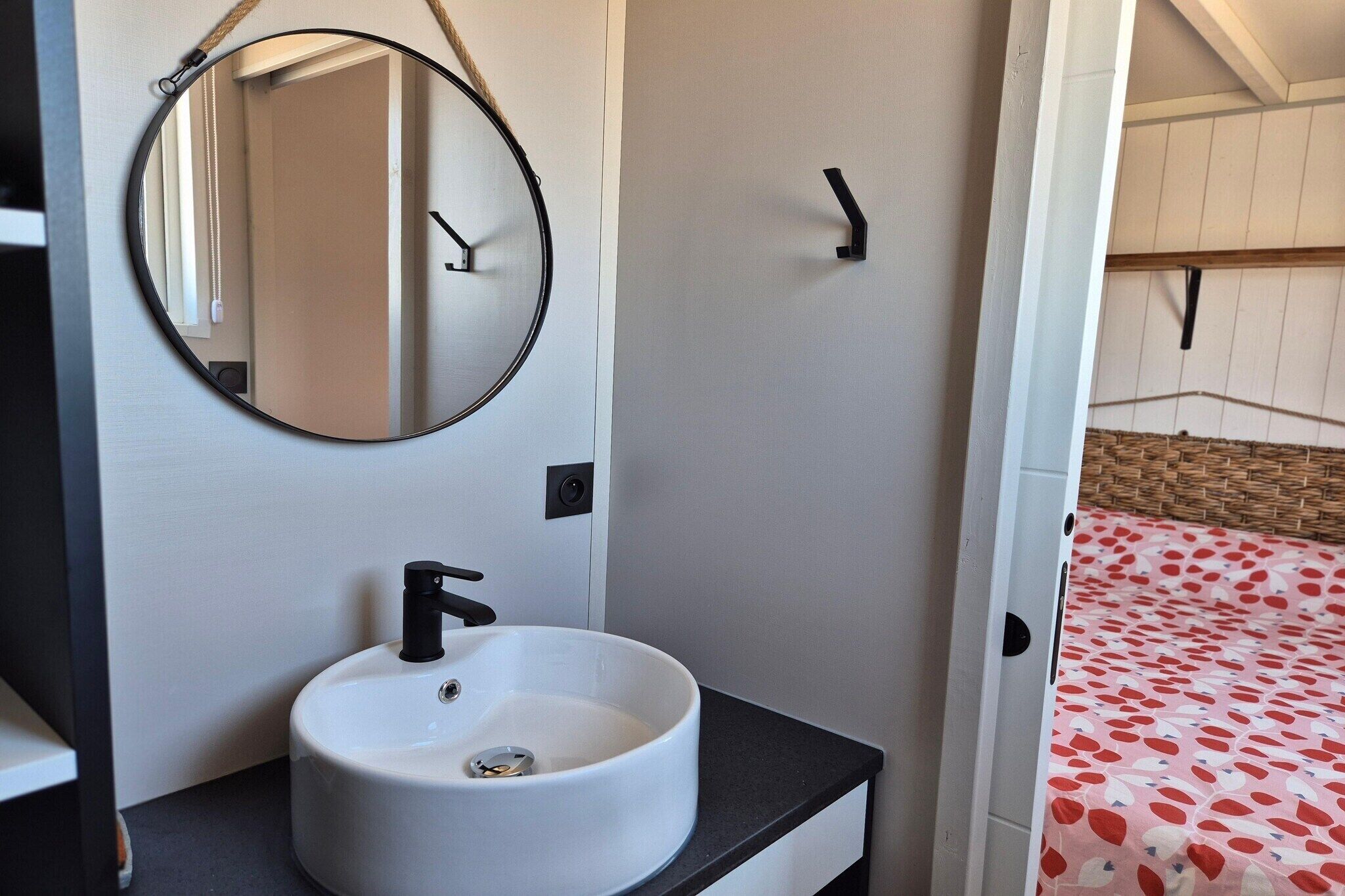 A bathroom with a round mirror, a white sink, and a black faucet.