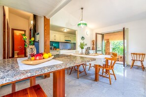 Eine moderne Küche mit Granit-Arbeitsplatten, Holzstühlen und einem Esstisch.