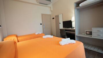 Une chambre d’hôtel avec deux lits, un bureau avec un ordinateur, une armoire et un climatiseur fixé au mur.