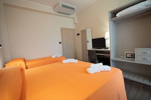 Una habitación de hotel con dos camas, un escritorio con computadora, un armario y aire acondicionado instalado en la pared.