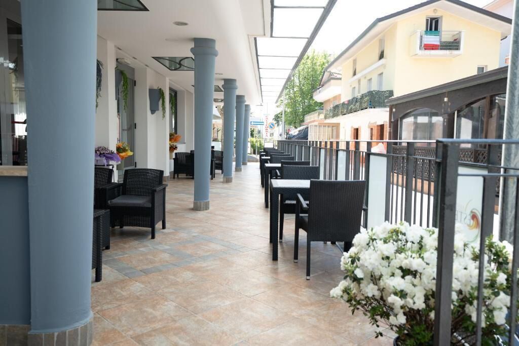 An outdoor café with tables and chairs, a tiled floor, and a glass ceiling.