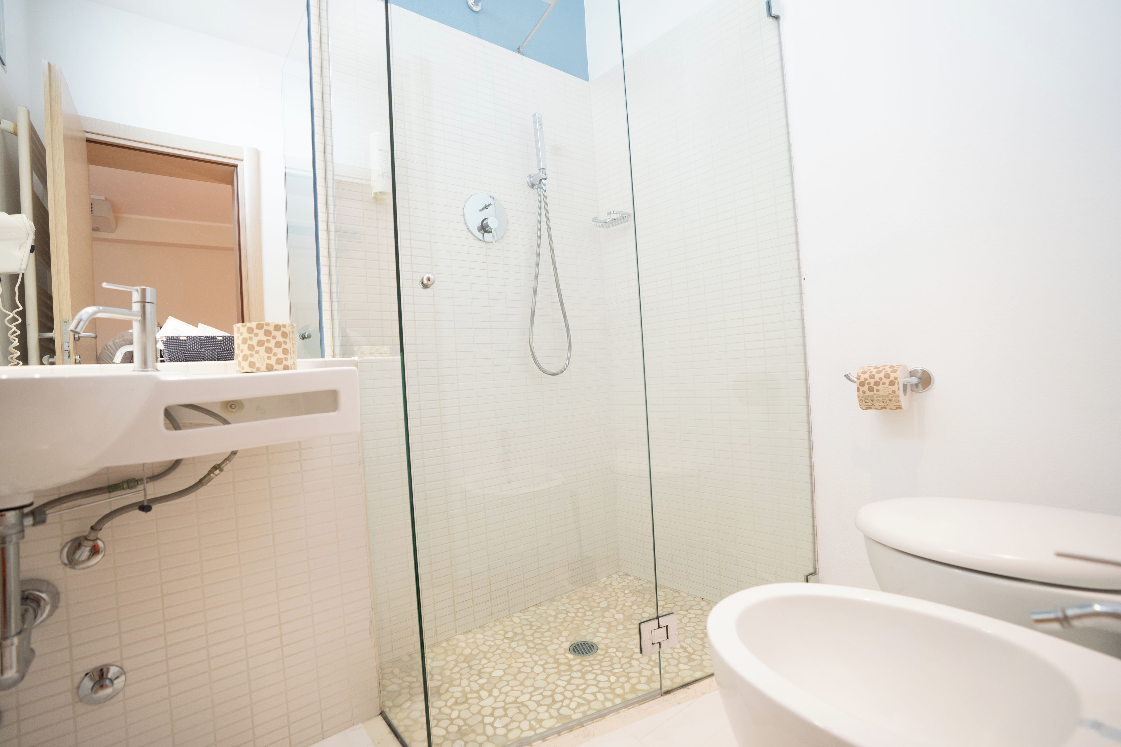 Een moderne badkamer met een douchecabine van glas, een witte wastafel en een toilet.