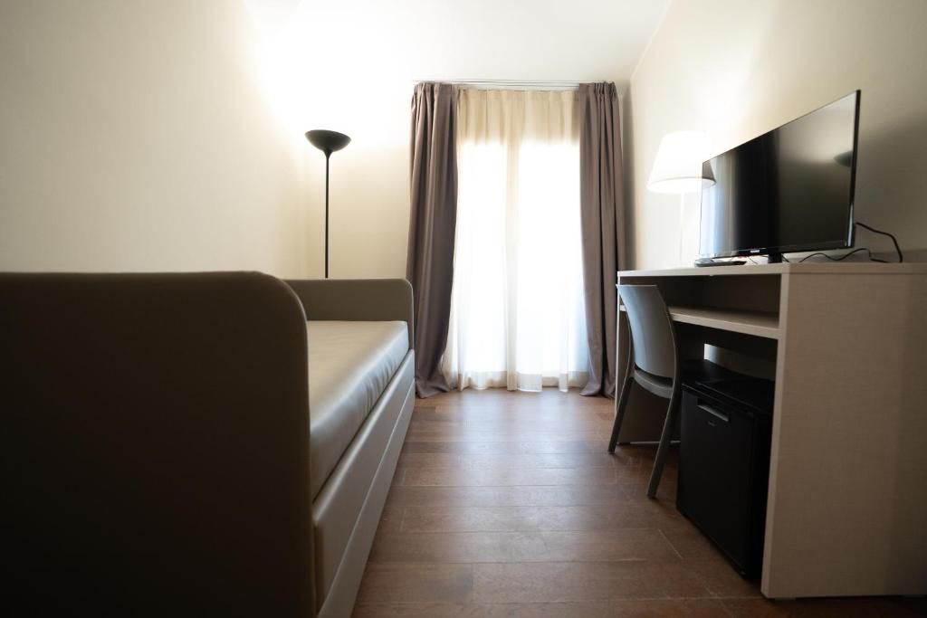 A room with a bed, a desk, a television, and a lamp.