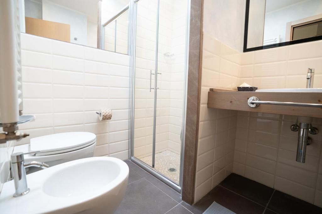 Ein Badezimmer mit Toilette, Waschbecken, Dusche und Spiegel.