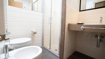 Ein Badezimmer mit Toilette, Waschbecken, Dusche und Spiegel.