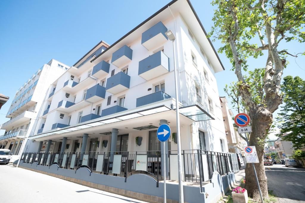 Ein mehrstöckiges Hotel mit Balkonen, einem überdachten Eingang und einem Verbotsschild für Fahrzeuge.