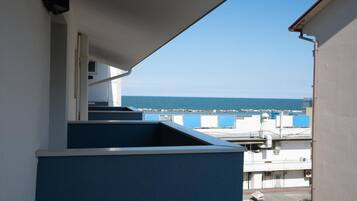 Un balcon avec vue sur la mer et un bâtiment en arrière-plan.