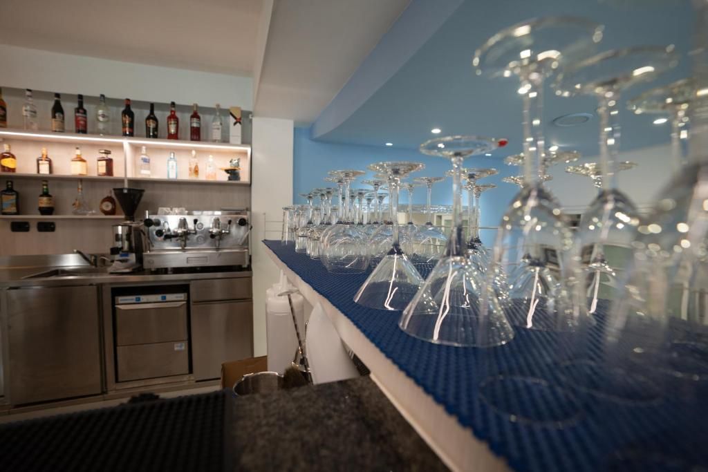 Un espace bar doté d’un long comptoir, de nombreuses bouteilles exposées sur des étagères, ainsi que de nombreux verres et verres à vin.