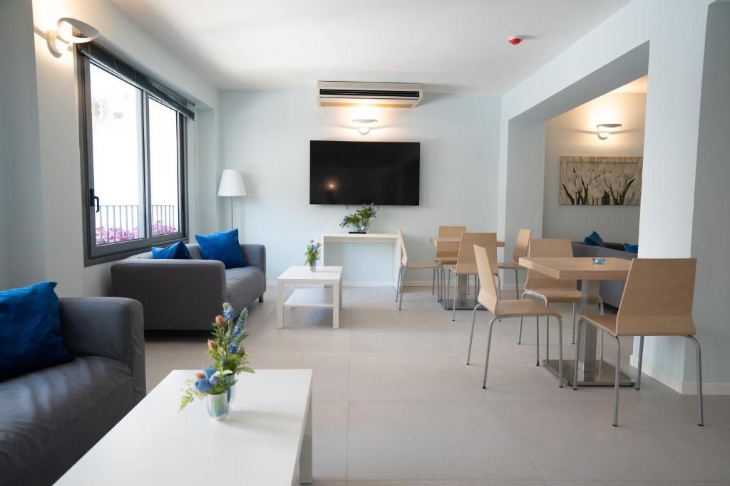 Una sala de estar moderna con un sofá, una mesa de centro, televisor y comedor con sillas y una mesa.