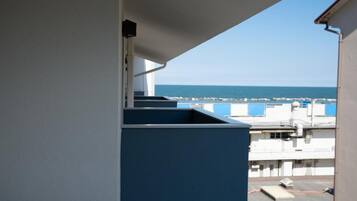 Ein Balkon mit Blick auf das Meer und Gebäude im Hintergrund.