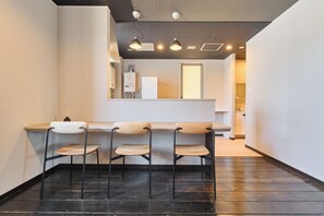 A modern kitchen with a bar area, three bar stools, and a visible water heater.