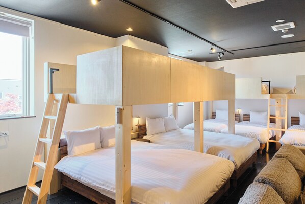 A hotel room with bunk beds, a ladder, and a window with a view.