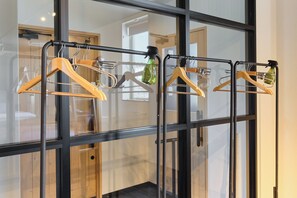 A clothing rack with hangers and bottles in a room with large windows.