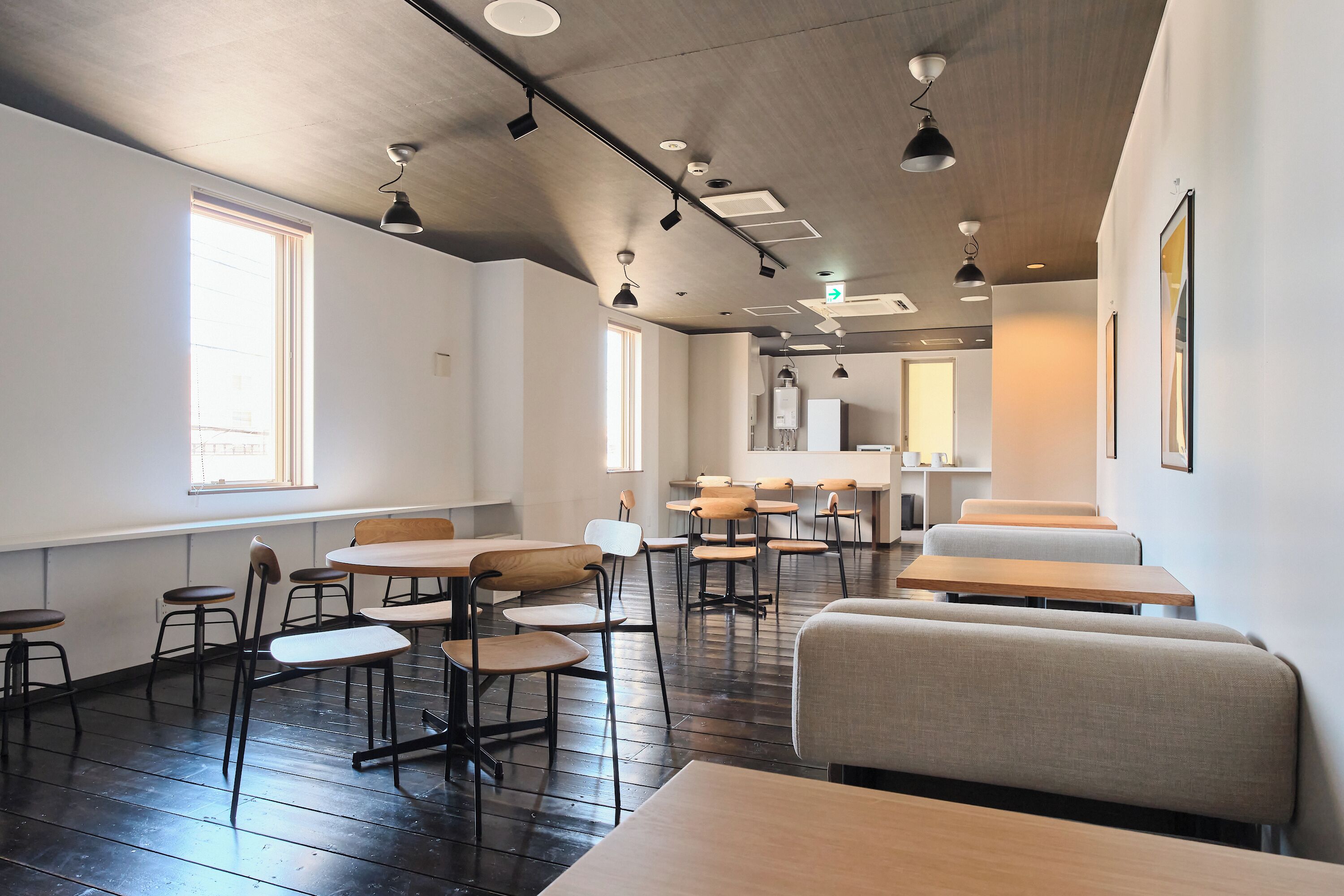 A modern interior with multiple seating areas, including tables and chairs, and a visible exit sign on the ceiling.