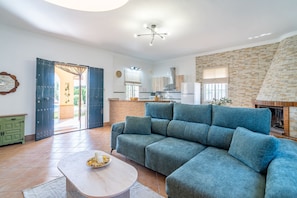 A modern living room with a sectional sofa, a round coffee table, and a fireplace. - Villa Manantial Holiday Home (La Puebla de Cazalla)