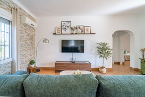 A living room with a TV, sofa, and decorative items. - Villa Manantial Holiday Home (La Puebla de Cazalla)