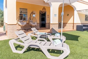Eine Terrasse mit Liegestühlen, einer Hängematte und einem Tisch mit einem Handtuch.