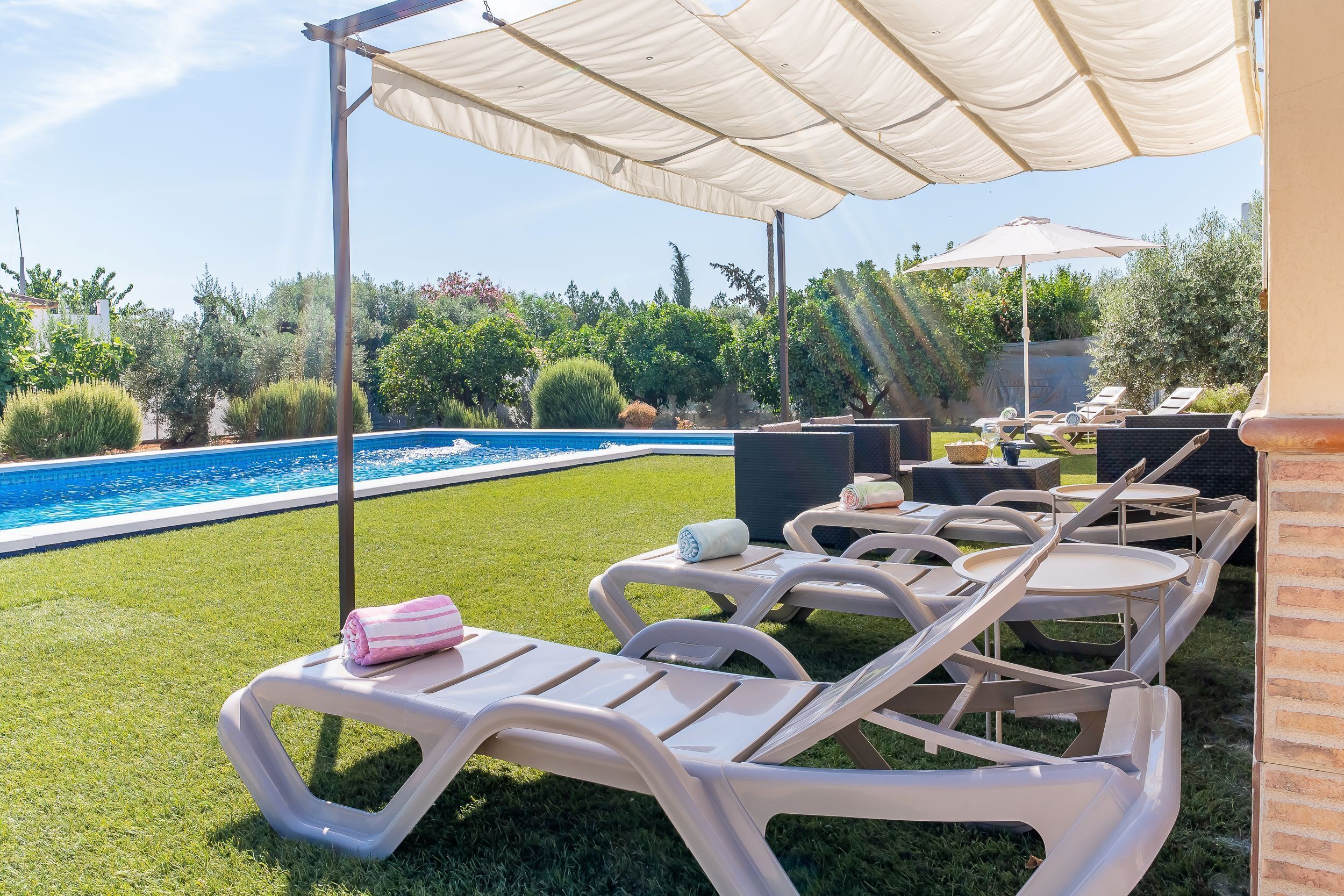 Ein Poolbereich mit Liegestühlen, einem Sonnenschirm und einem Pool.