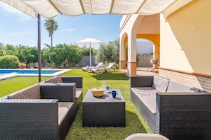 A patio area with wicker furniture, a pool, and a covered seating area. - Villa Manantial Holiday Home (La Puebla de Cazalla)