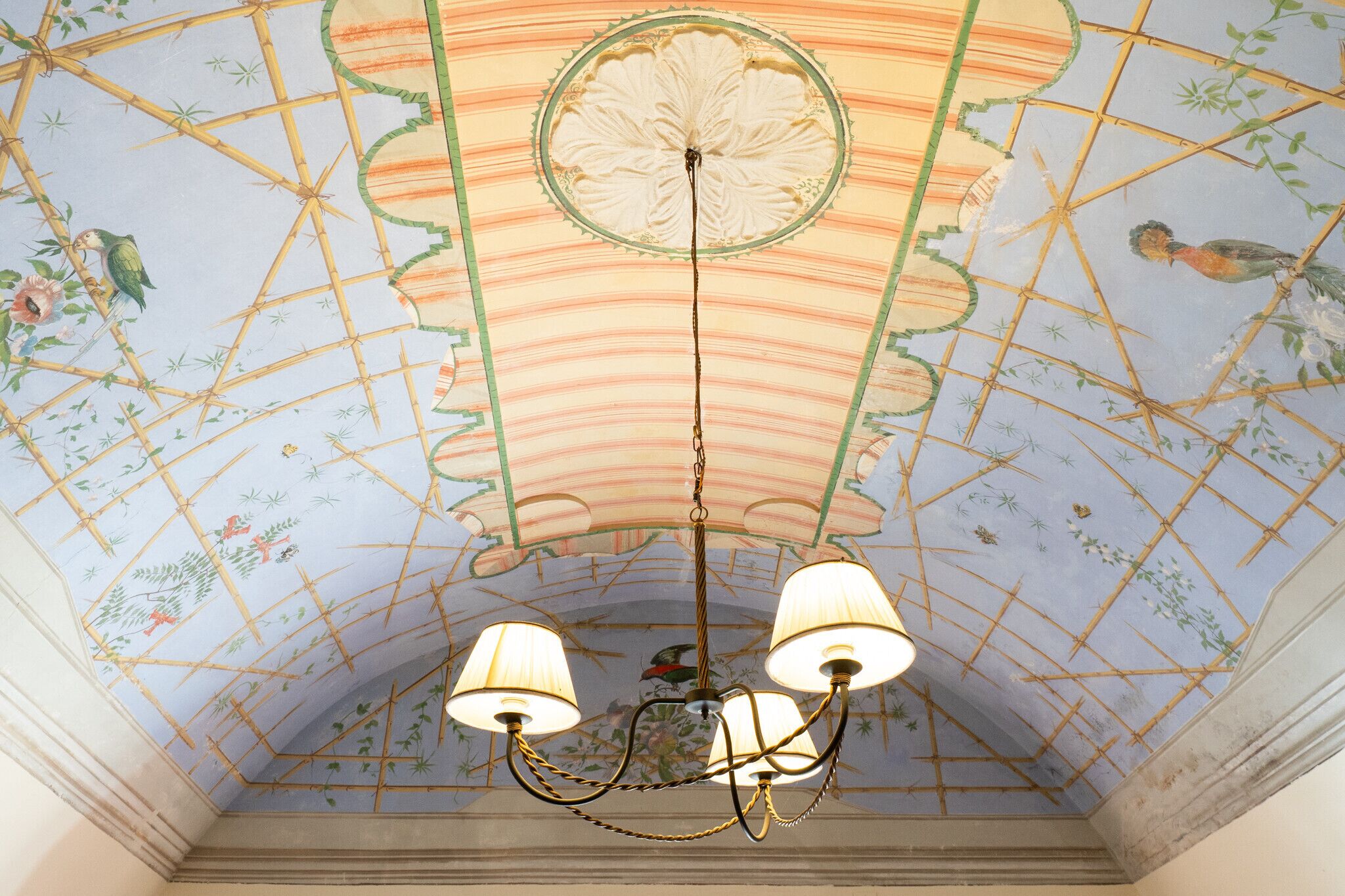 A ceiling with a floral pattern and a chandelier with three lamps.