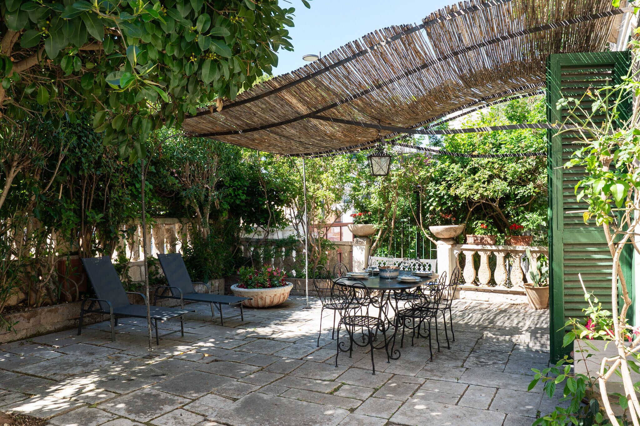 A patio with a table and chairs, a pergola, and potted plants.