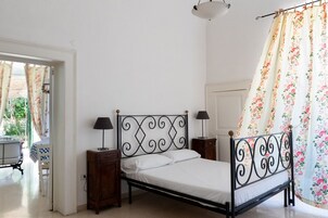 A bedroom with a bed, two bedside tables, a nightstand, a window with curtains, and a door.