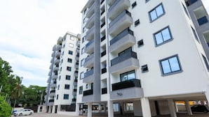 A multi-story residential building with balconies, a covered parking area, and a clear sky. - Radium Residences View Palace Apartment (Mombasa)