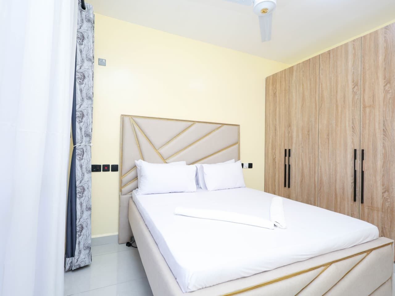 Een slaapkamer met een bed, een kledingkast en een plafondventilator.