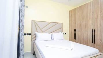 Een slaapkamer met een bed, een kledingkast en een plafondventilator.