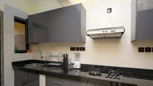 A modern kitchen with a black countertop, stainless steel appliances, and grey cabinets. - Radium Residences View Palace Apartment (Mombasa)