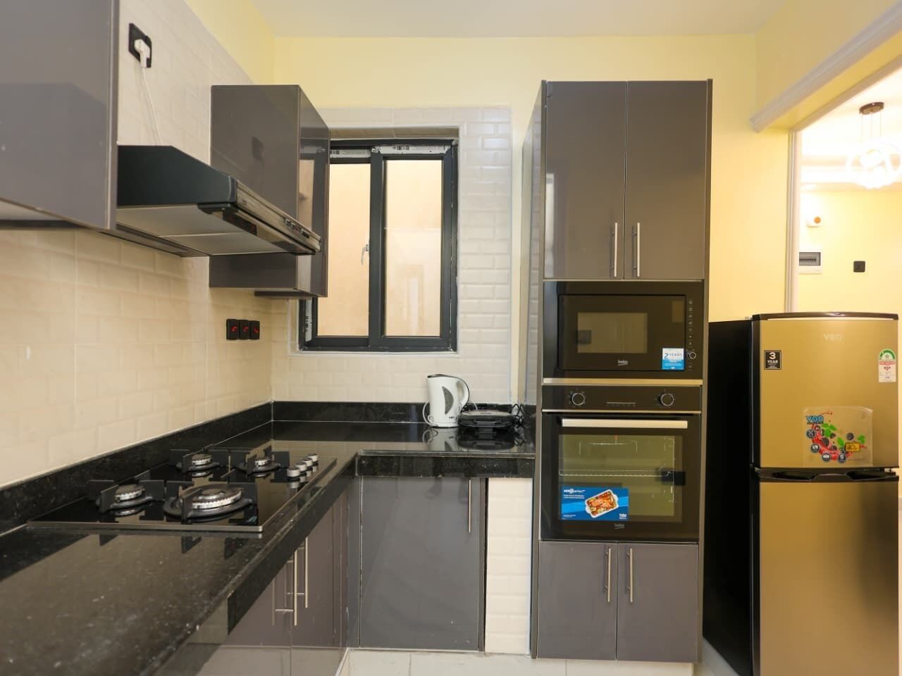 Una cocina equipada con estufa a gas, horno, microondas y refrigerador.