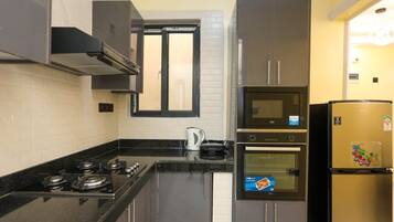 Una cocina equipada con estufa a gas, horno, microondas y refrigerador.